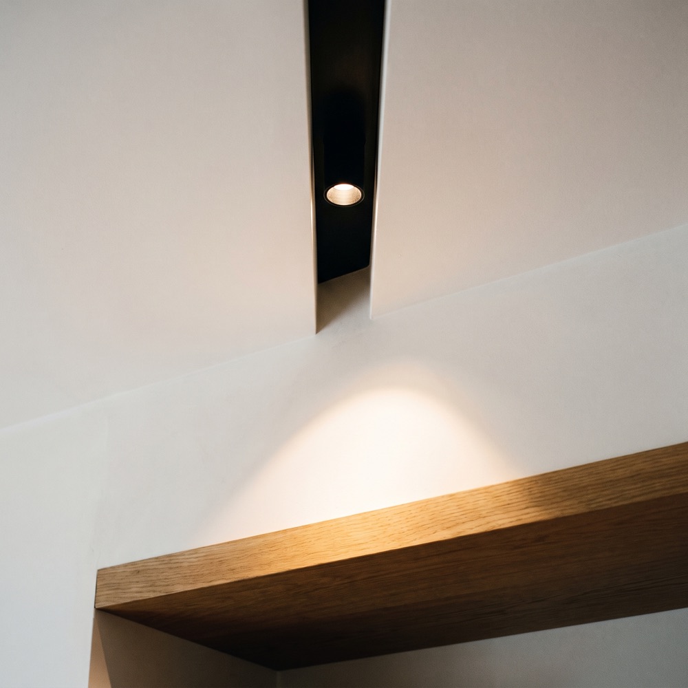 Recessed spotlight in a shadow-gap reveal, aimed at a shelf edge
