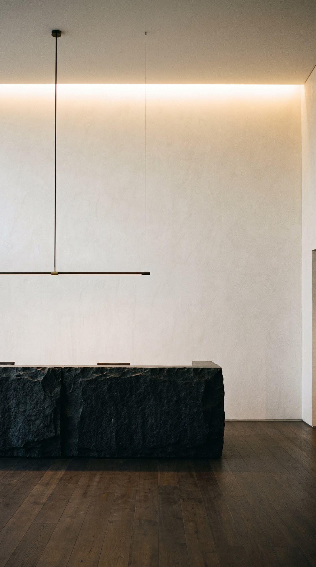 Reception with a stone desk against a plaster wall lit by a concealed cove, Forsyth Barr